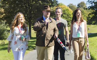 Tour guide leading a small group through the scenic Cotswolds countryside.