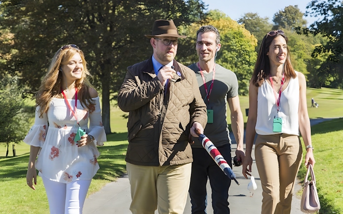 Tour guide leading a small group through the scenic Cotswolds countryside.