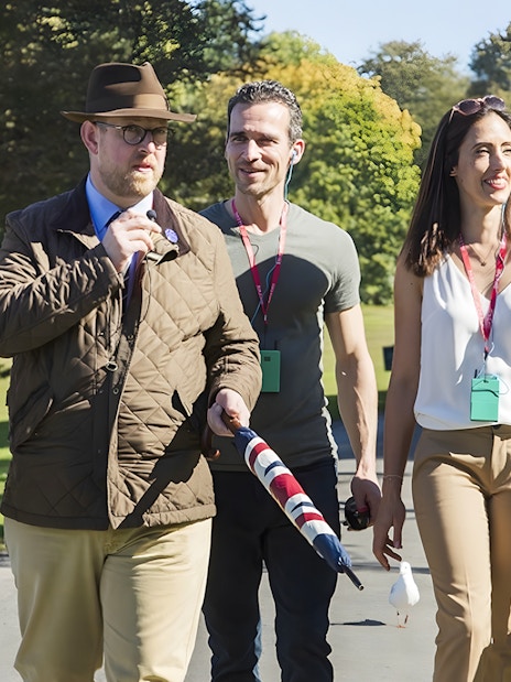 Tour guide leading a small group through the scenic Cotswolds countryside.