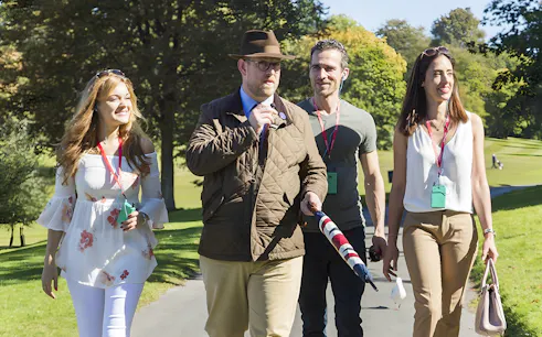 Tour guide leading a small group through the scenic Cotswolds countryside.