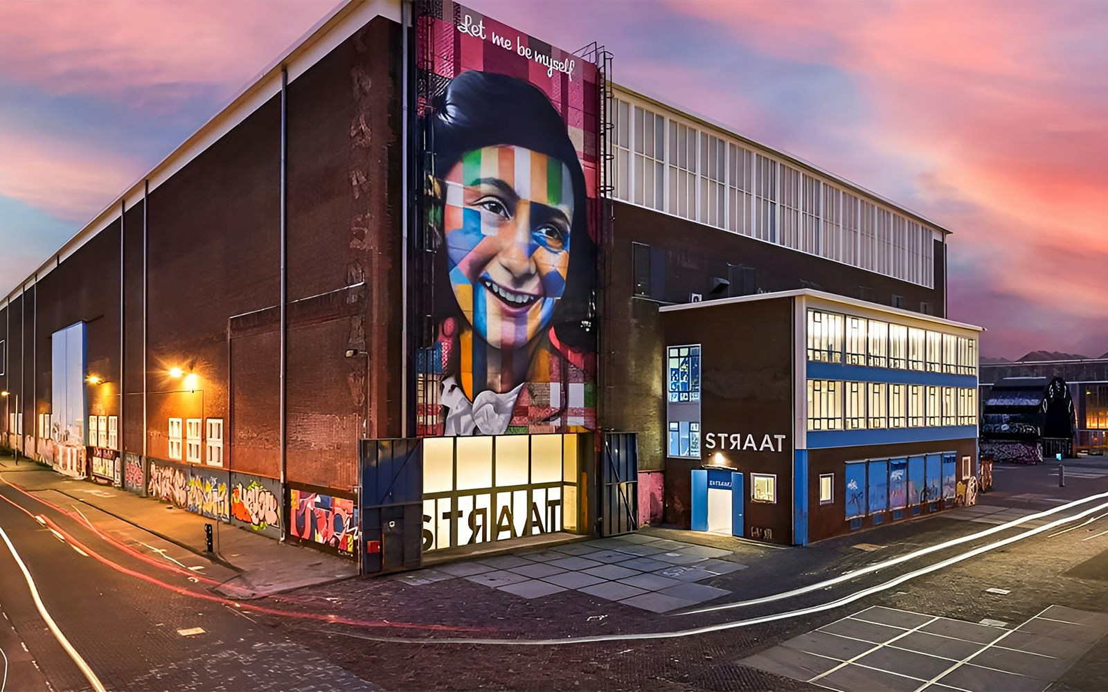 STRAAT Museum exterior with vibrant street art, Amsterdam canal cruise boat passing by.