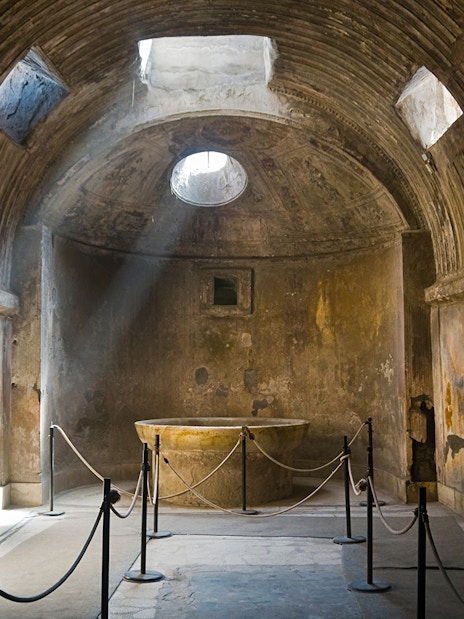 Ancient room in Pompeii with sunlight through ceiling, part of guided tour.