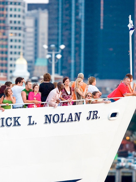 People on a cruise ship in Boston, enjoying city skyline views.