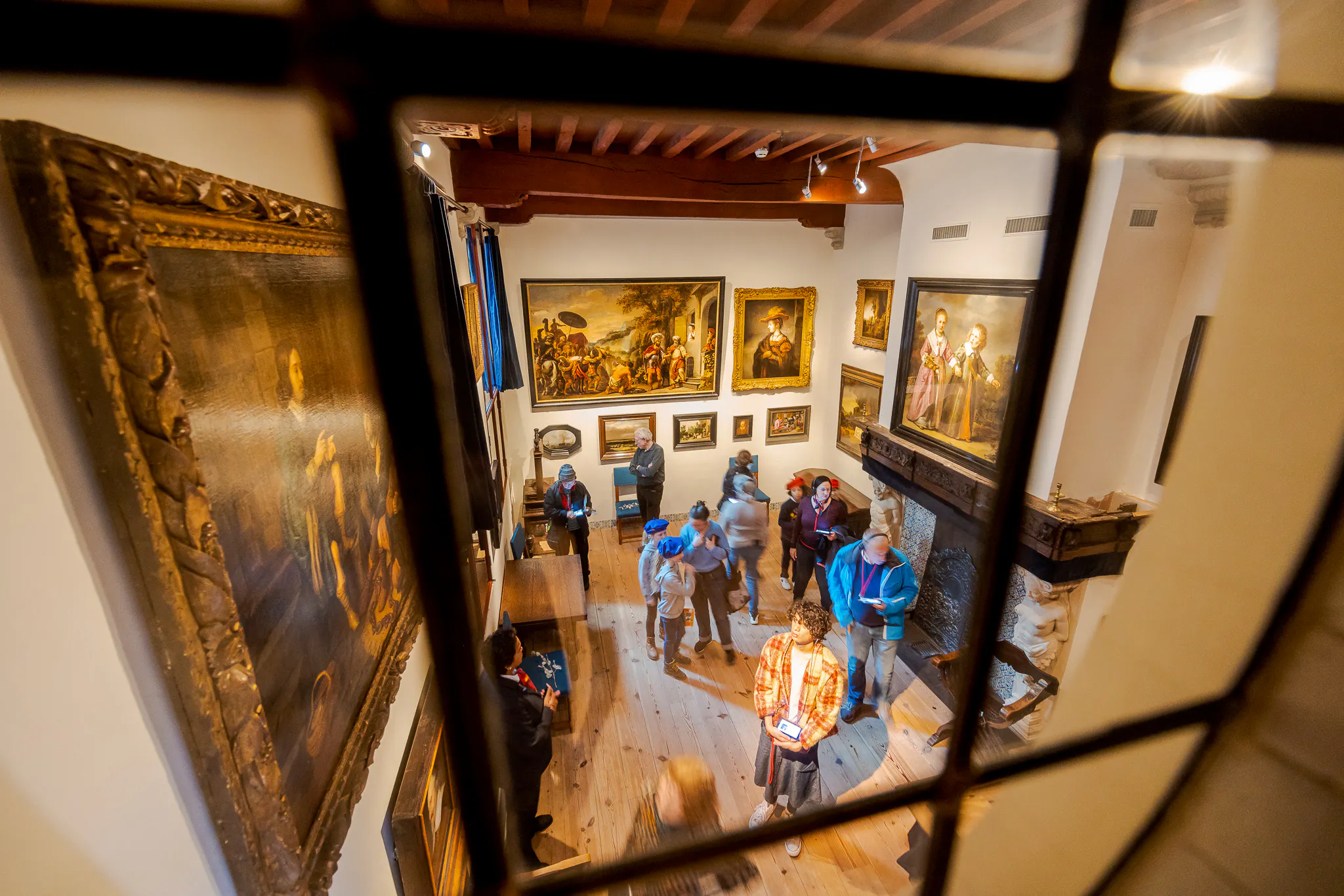 Visitors exploring Rembrandt House Museum in Amsterdam, viewing paintings and exhibits.
