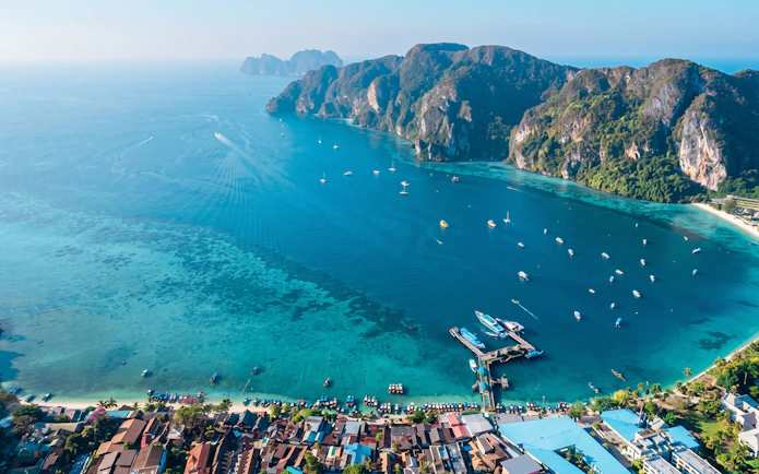 Aerial view of Phi Phi Island's coastline with boats in turquoise water, Thailand.