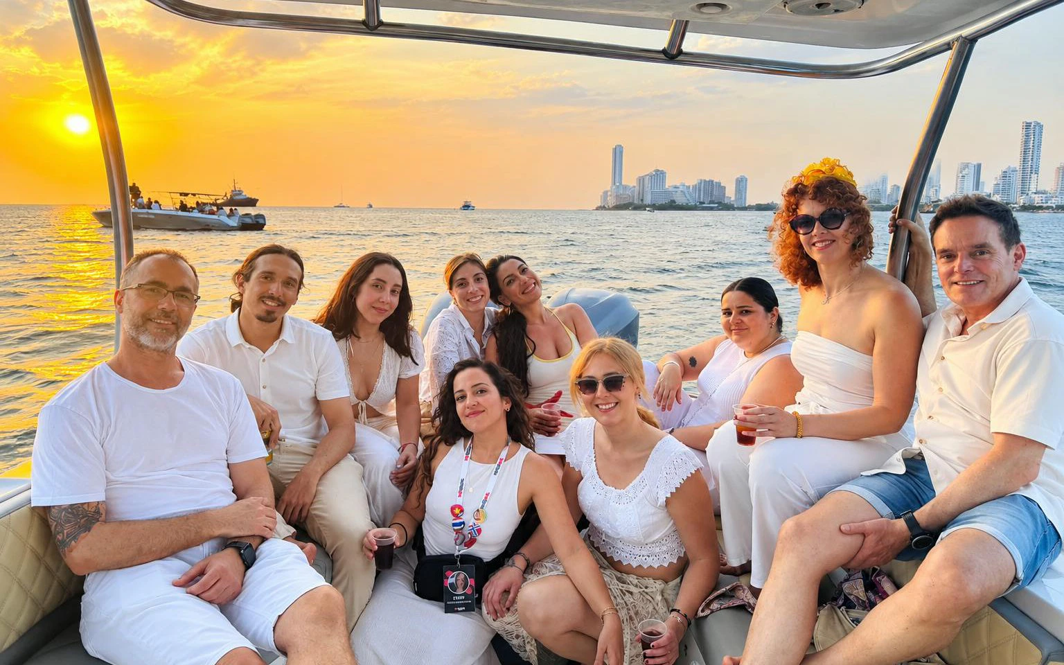 Group enjoying a sunset party cruise in Cartagena with city skyline in the background.