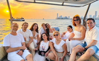 Group enjoying a sunset party cruise in Cartagena with city skyline in the background.