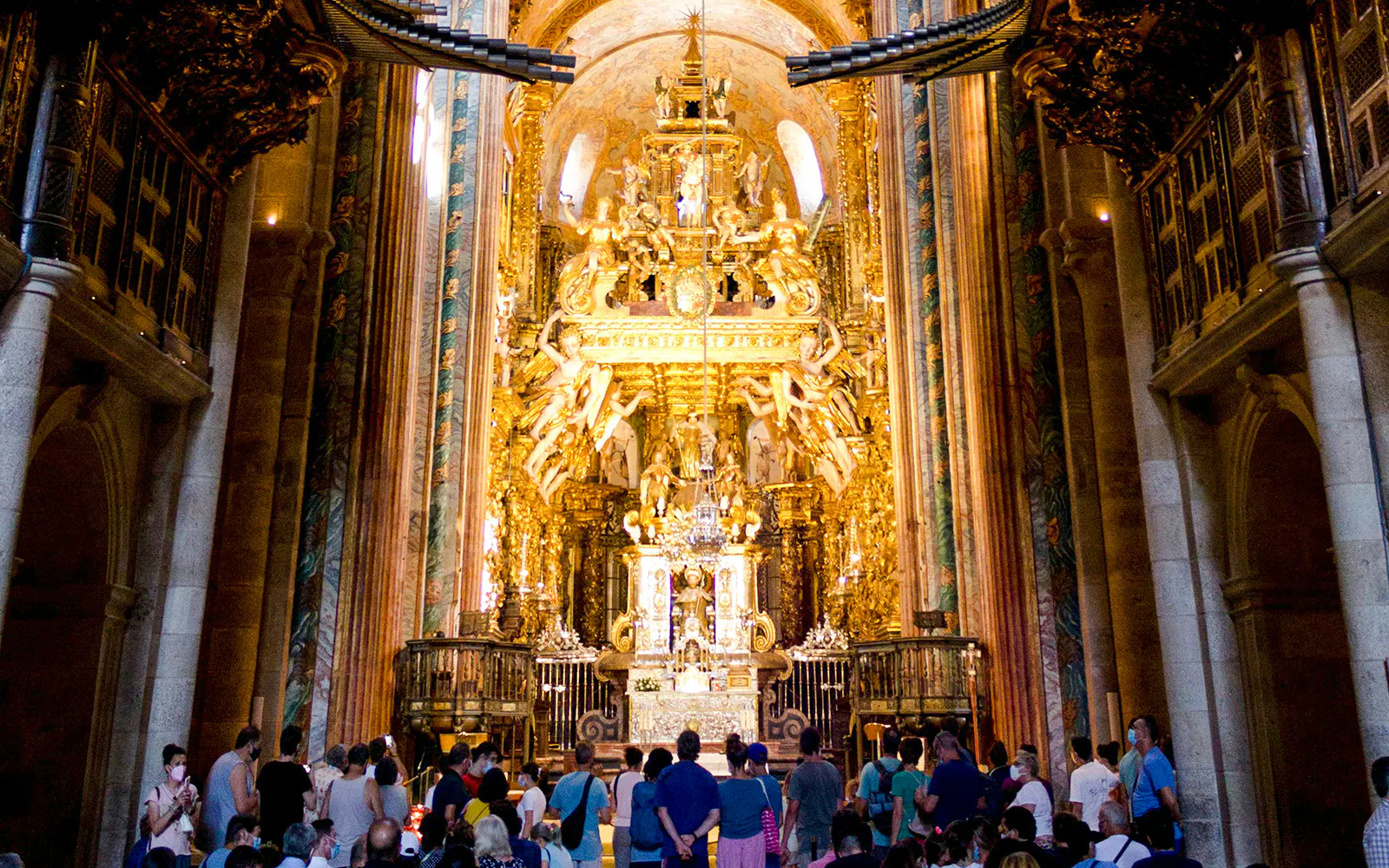 Visitors inside Santiago's Cathedral, Galicia, Spain, viewing the ornate golden altar.