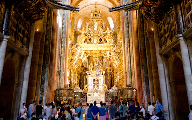 Visitors inside Santiago's Cathedral, Galicia, Spain, viewing the ornate golden altar.