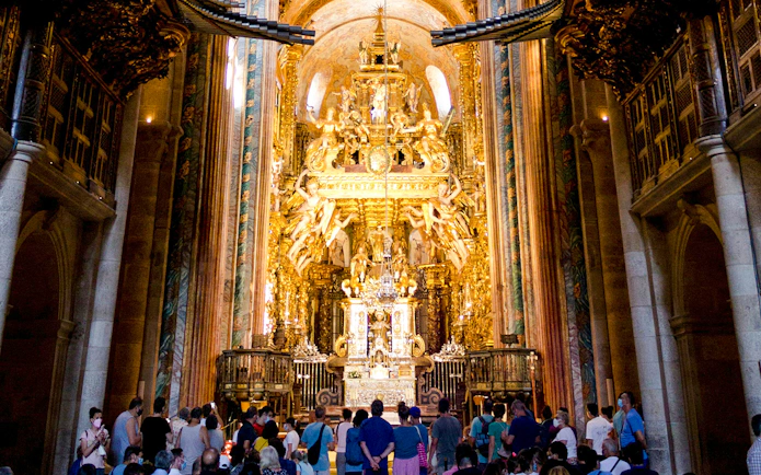 Visitors inside Santiago's Cathedral, Galicia, Spain, viewing the ornate golden altar.