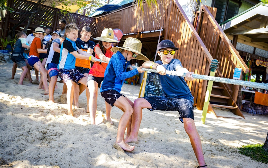 Kids playing tug-of-war on sandy beach at South Sea Island, Fiji.