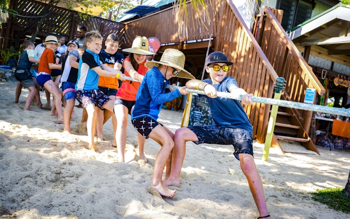 Kids playing tug-of-war on sandy beach at South Sea Island, Fiji.