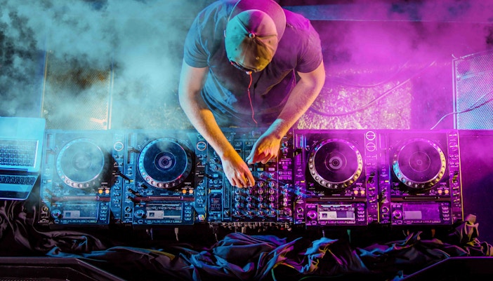 DJ performing at a New Year event in Athens with vibrant lights and smoke effects.