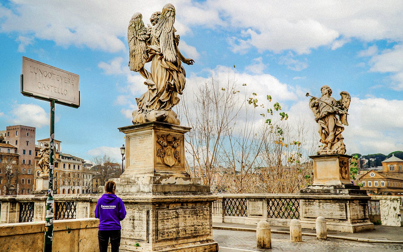 Statues on Ponte Sant'Angelo near Castel Sant'Angelo, Rome, with a tour guide in view.