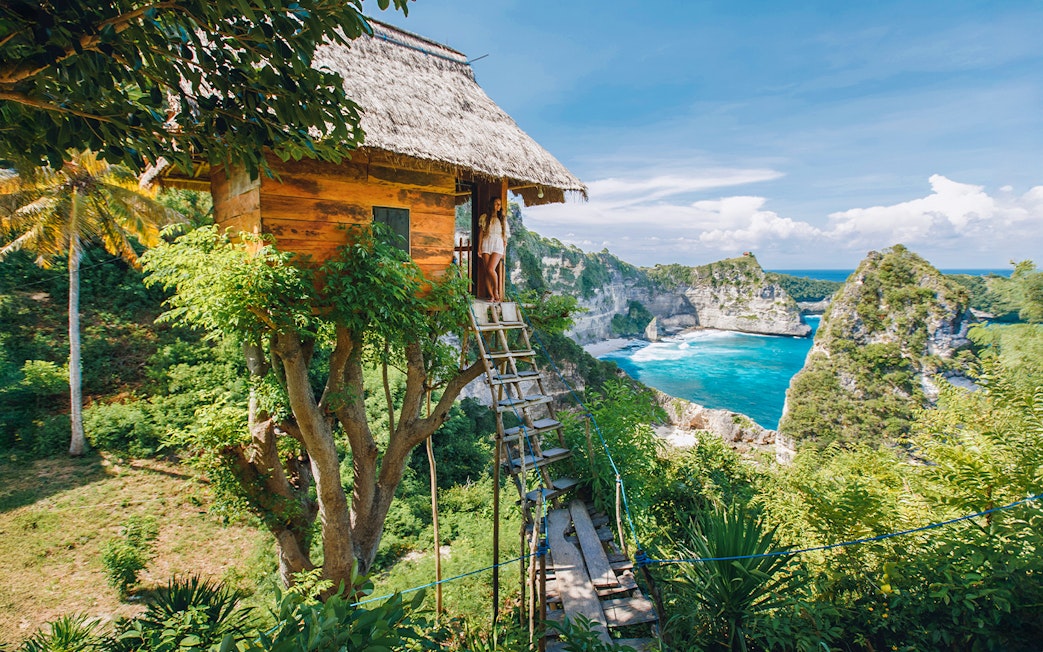Tourists at Rumah Pohon Tree House overlooking ocean in Nusa Penida, Bali.