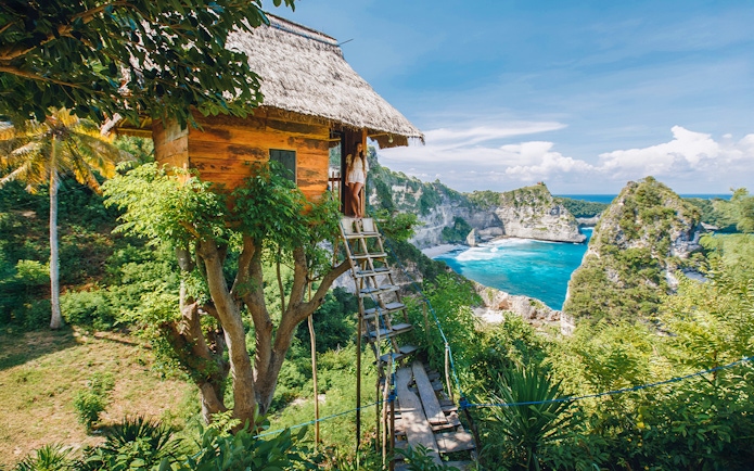 Tourists at Rumah Pohon Tree House overlooking ocean in Nusa Penida, Bali.