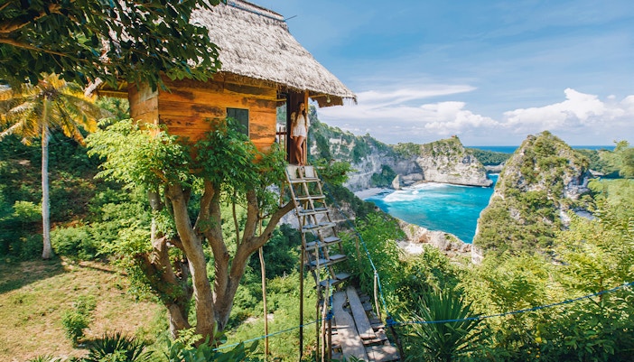 Tourists at Rumah Pohon Tree House overlooking ocean in Nusa Penida, Bali.