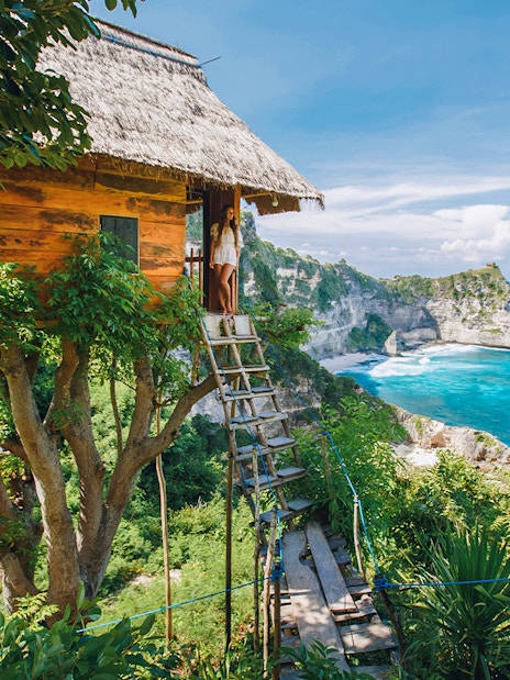 Tourists at Rumah Pohon Tree House overlooking ocean in Nusa Penida, Bali.