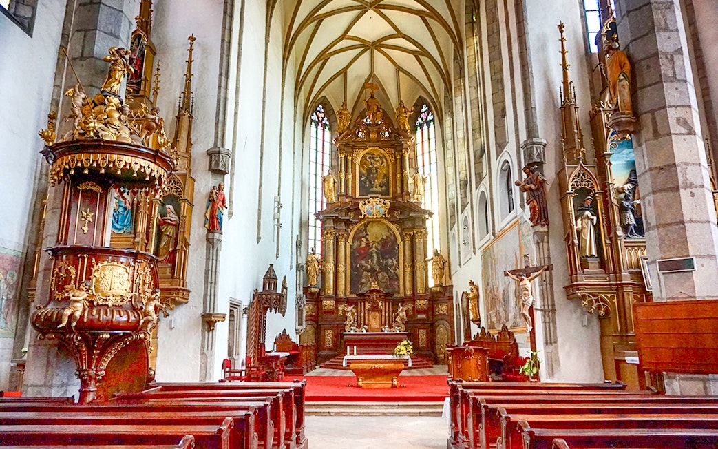 St. Vitus Cathedral interior in Cesky Krumlov with Gothic architecture and stained glass windows.
