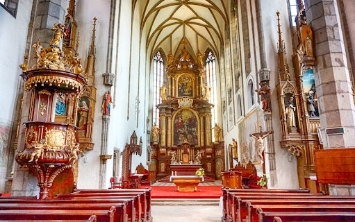 St. Vitus Cathedral interior in Cesky Krumlov with Gothic architecture and stained glass windows.