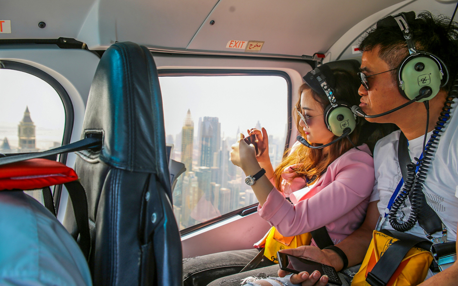 Couple photographing Dubai skyline from helicopter.