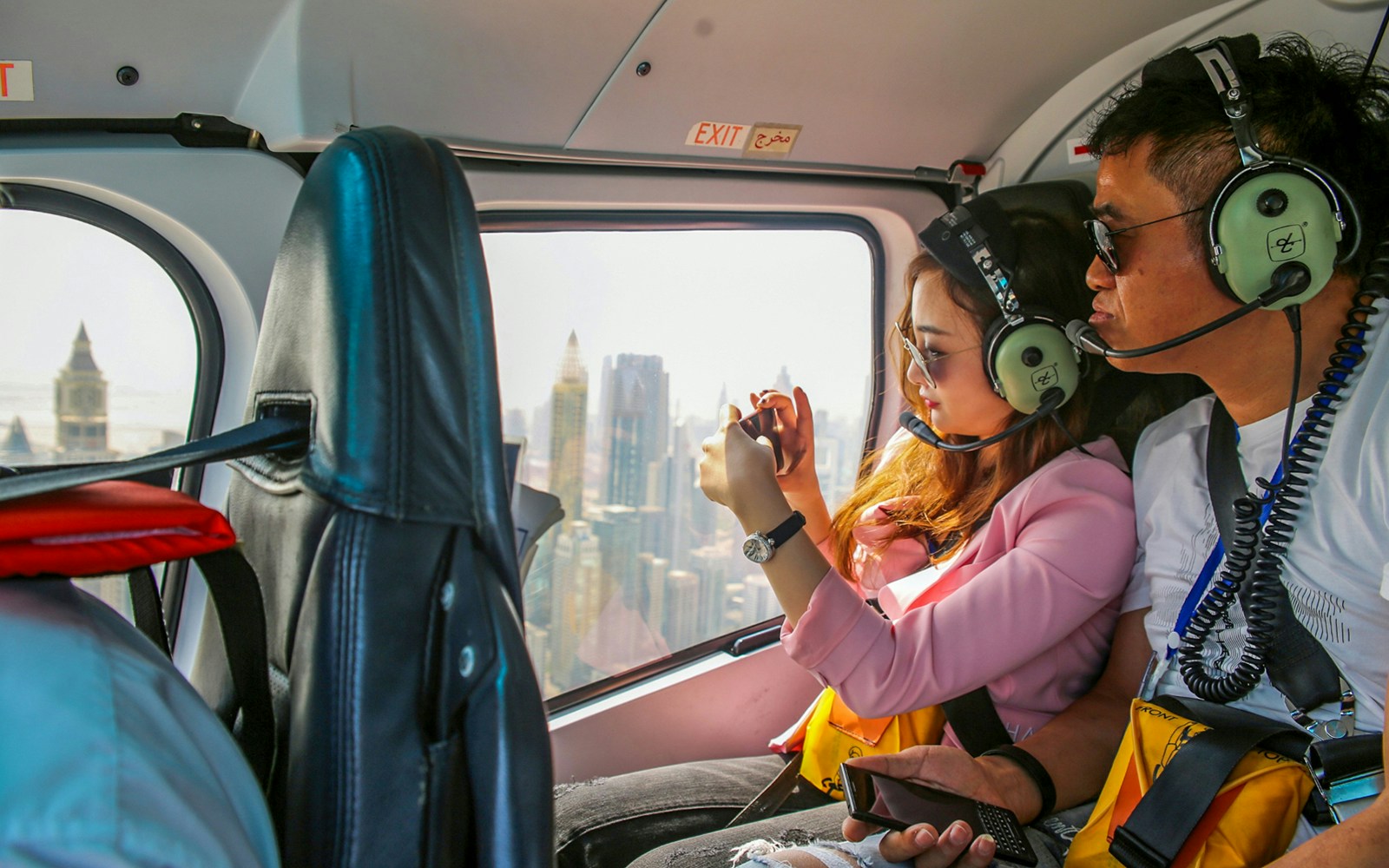 Couple photographing Dubai skyline from helicopter.