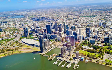 Aerial view of Perth city skyline along the Swan River, showcasing skyscrapers and waterfront.