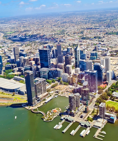 Aerial view of Perth city skyline along the Swan River, showcasing skyscrapers and waterfront.