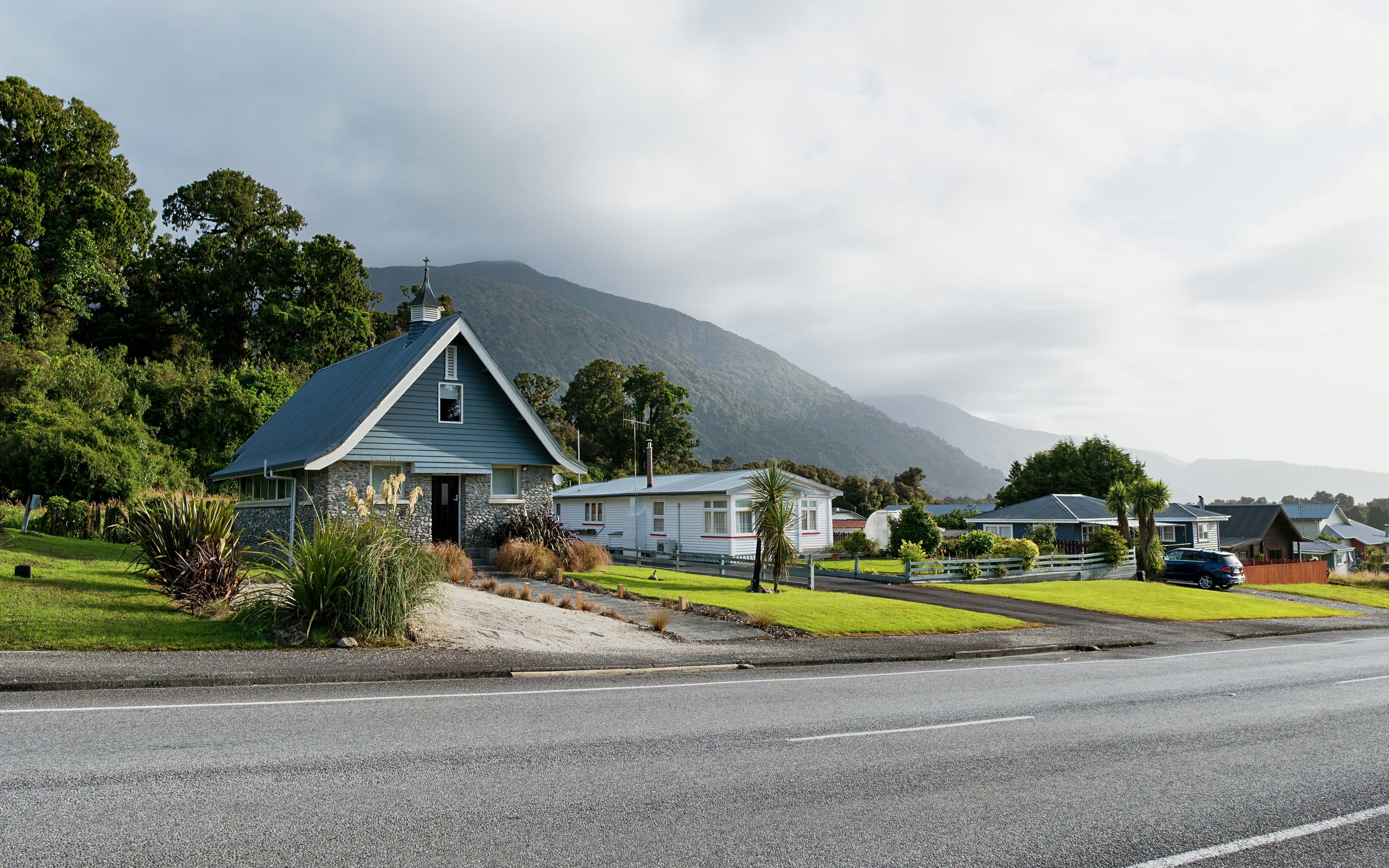 Houses with mountain backdrop in Franz Josef village, New Zealand.