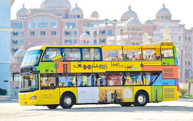 Doha hop-on hop-off tour bus in front of traditional architecture.
