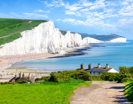 Seven Sisters Chalk Cliffs overlooking the English Channel with coastal path and cottages.