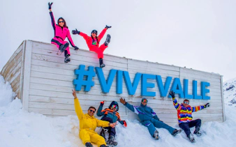 Tourists enjoying snow at Valle Nevado with #ViveValle sign.