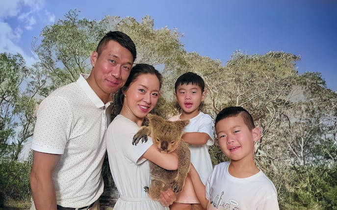 Family holding a koala at Kuranda Koala Gardens, Australia.