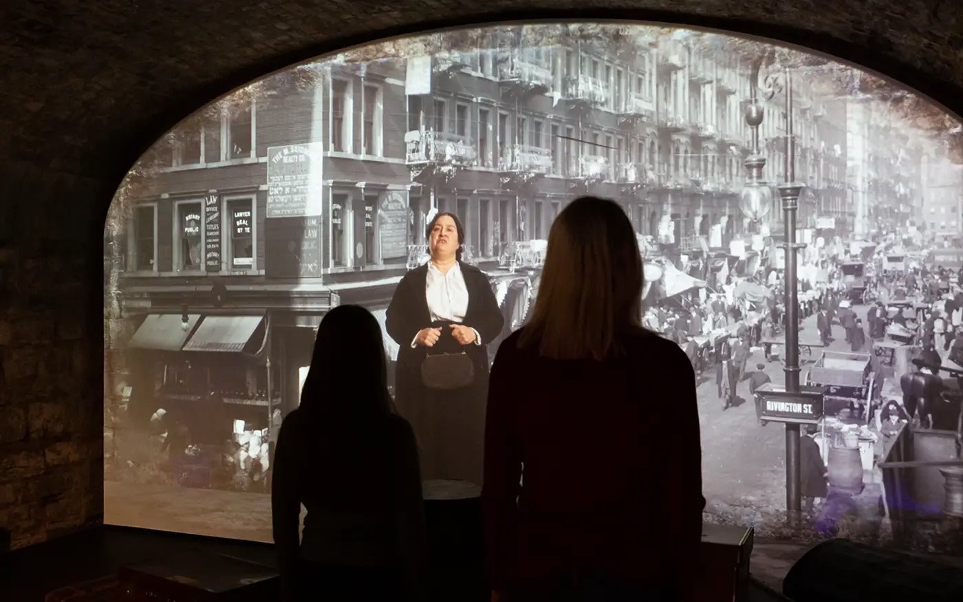 Visitors viewing a historical street scene projection at an epic museum exhibit.