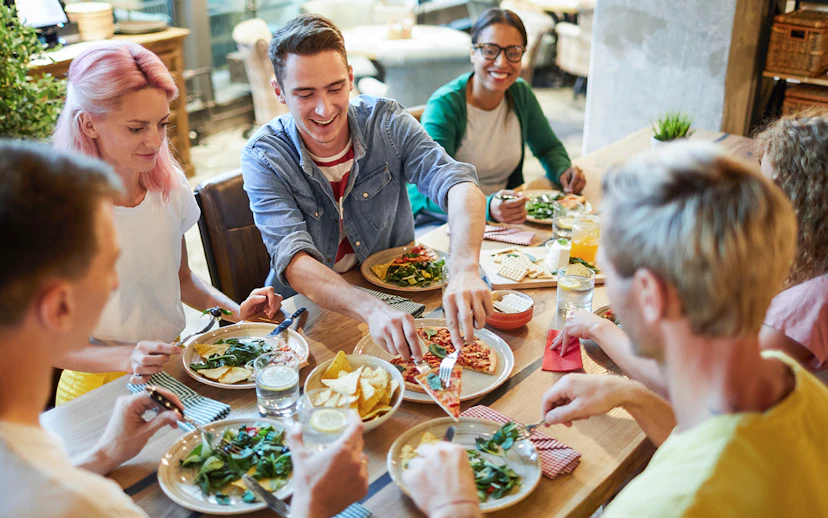 Group of friends enjoying Italian pizza at a restaurant.