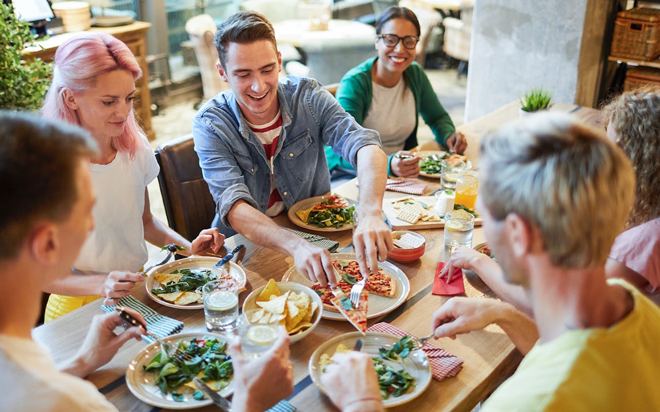 Group of friends enjoying Italian pizza at a restaurant.