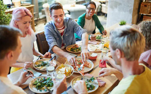 Group of friends enjoying Italian pizza at a restaurant.