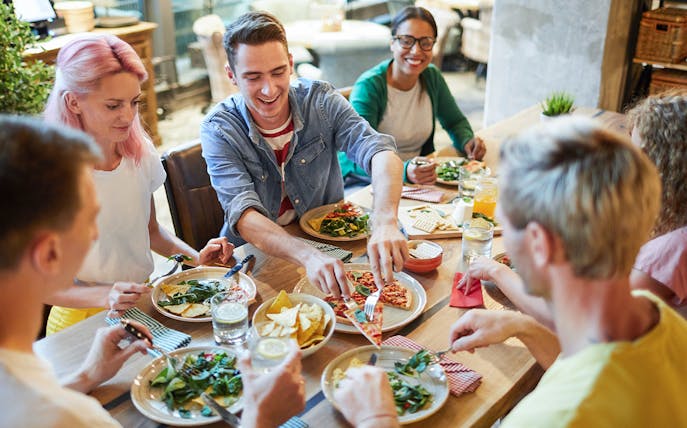 Group of friends enjoying Italian pizza at a restaurant.