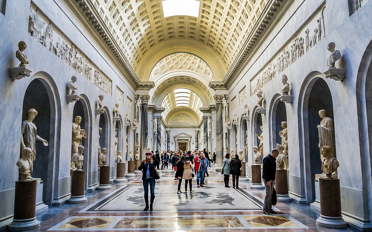 Visitors exploring sculpture gallery in Vatican Museums.
