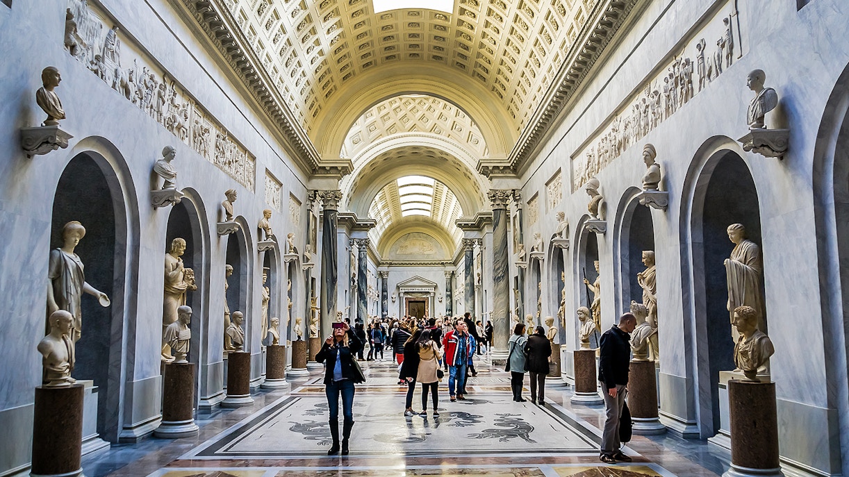 Vatican Museums sculptures display with visitors exploring the gallery.