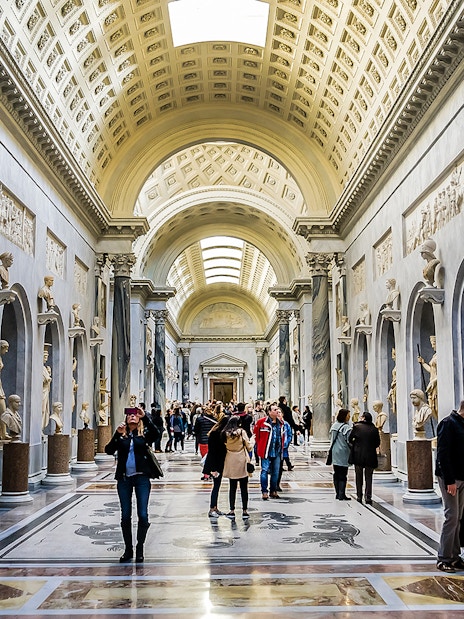 Visitors exploring sculpture gallery in Vatican Museums.