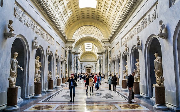 Visitors exploring sculpture gallery in Vatican Museums.