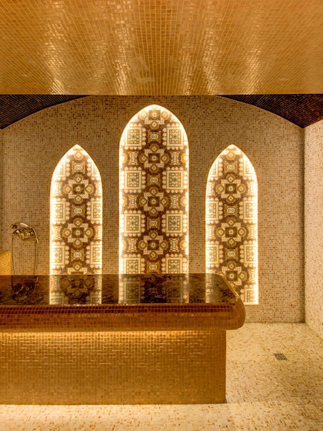 Interior of Sifa Hamam with ornate mosaic walls and central stone table.