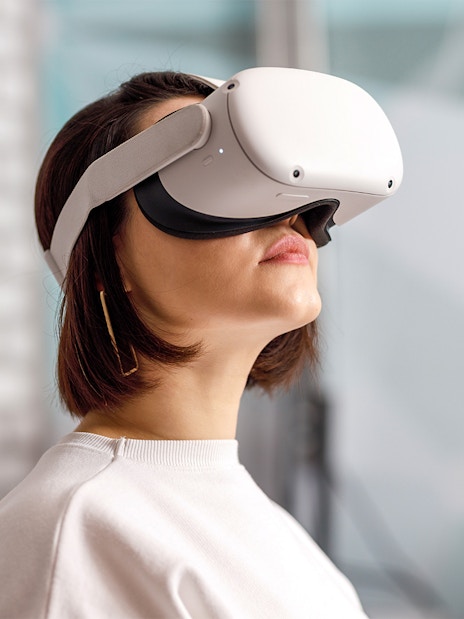 Person wearing VR goggles in a modern indoor setting.
