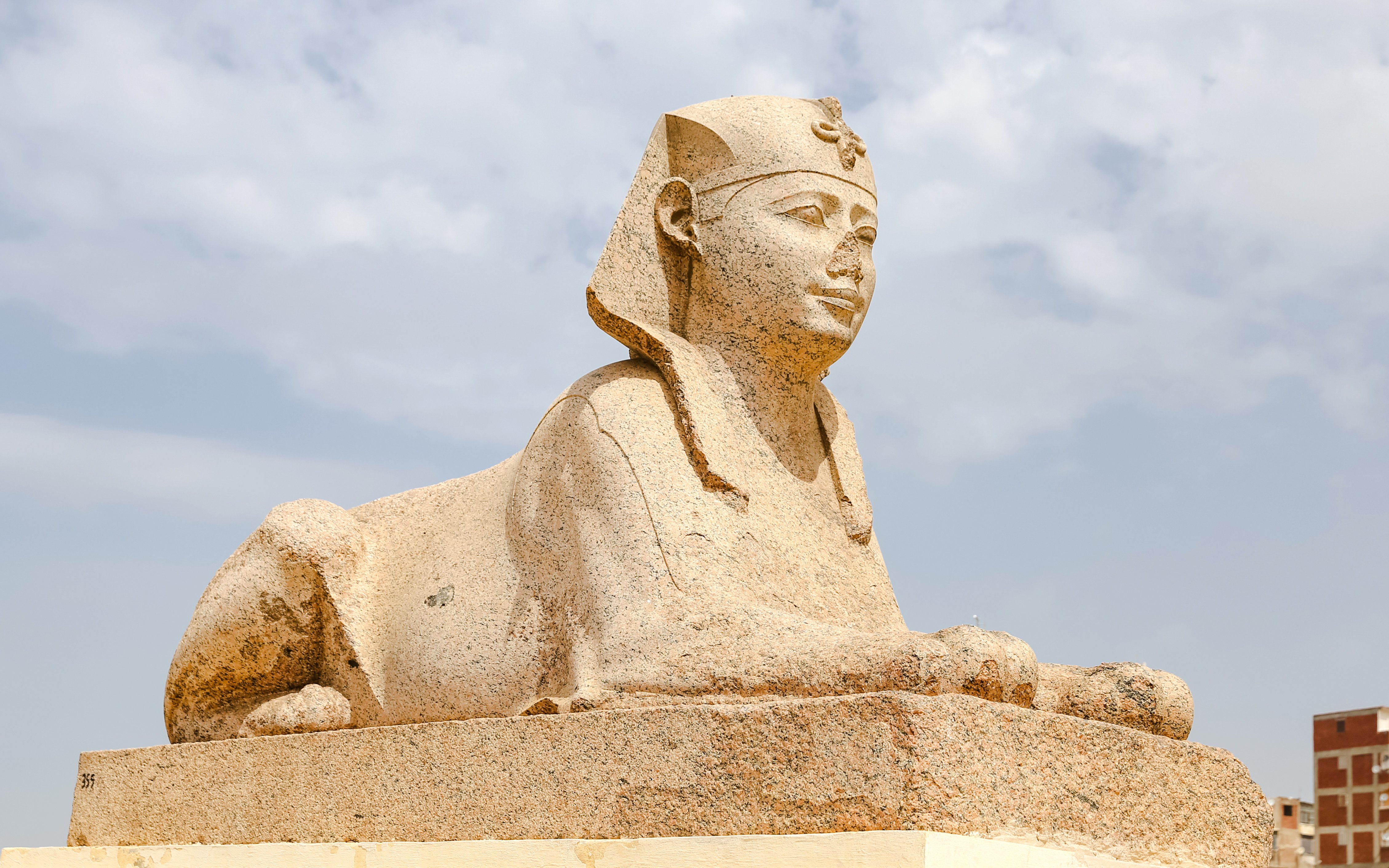 Sphinx statue at Serapeum of Alexandria, Egypt, under a cloudy sky.