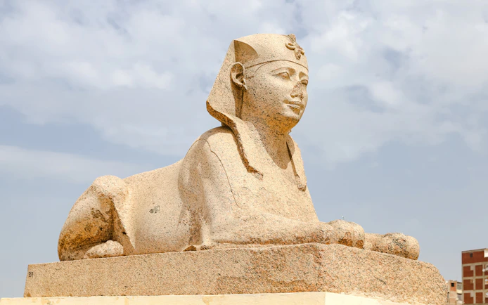 Sphinx statue at Serapeum of Alexandria, Egypt, under a cloudy sky.