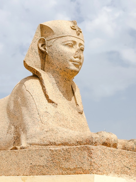 Sphinx statue at Serapeum of Alexandria, Egypt, under a cloudy sky.