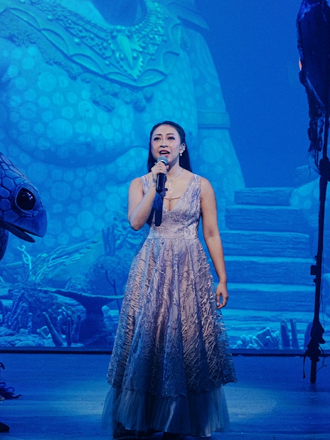 Performer singing at Varuna, Underwater Theatrical Dining Experience with aquatic-themed costumes.