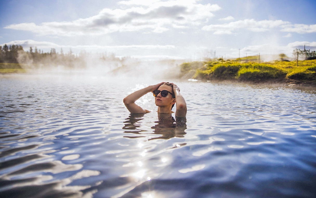 Guests enjoying geothermal waters at Secret Lagoon Gamla Laugin, Iceland.