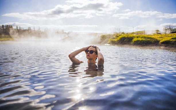 Guests enjoying geothermal waters at Secret Lagoon Gamla Laugin, Iceland.